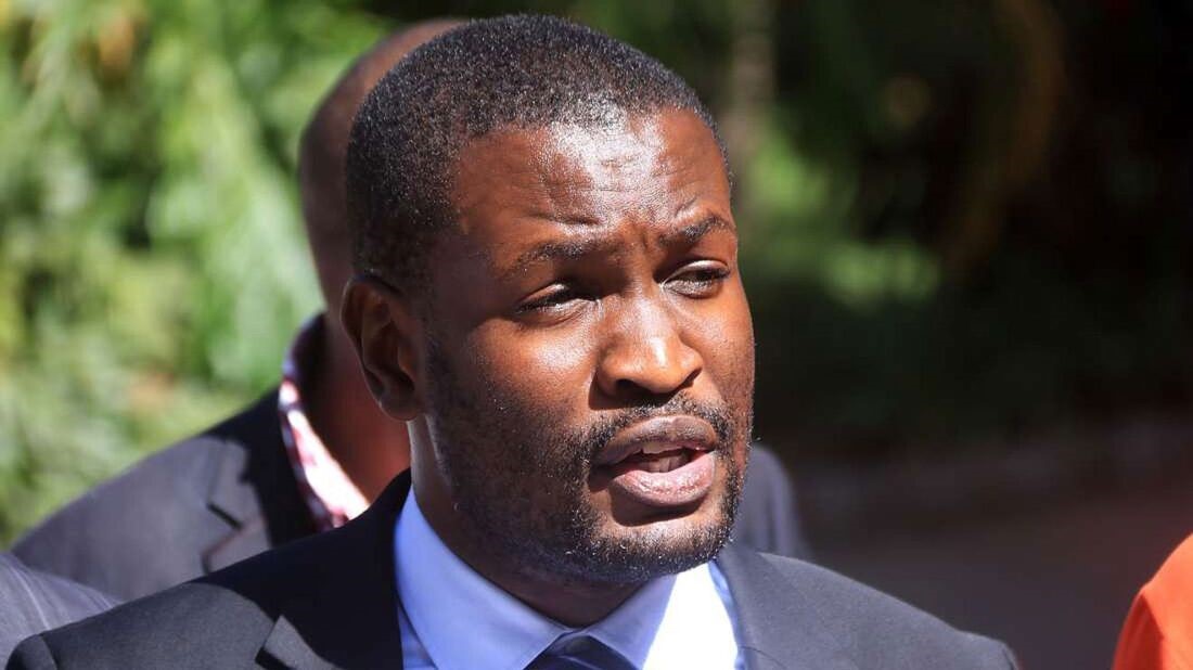 Edwin Sifuna speaking outdoors in a dark suit.