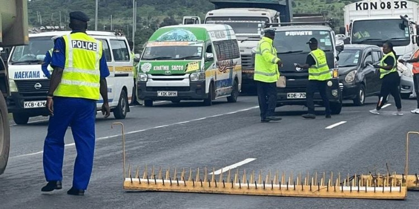 Traffic police officers stand beside vehicles on the Nairobi–Mombasa highway.