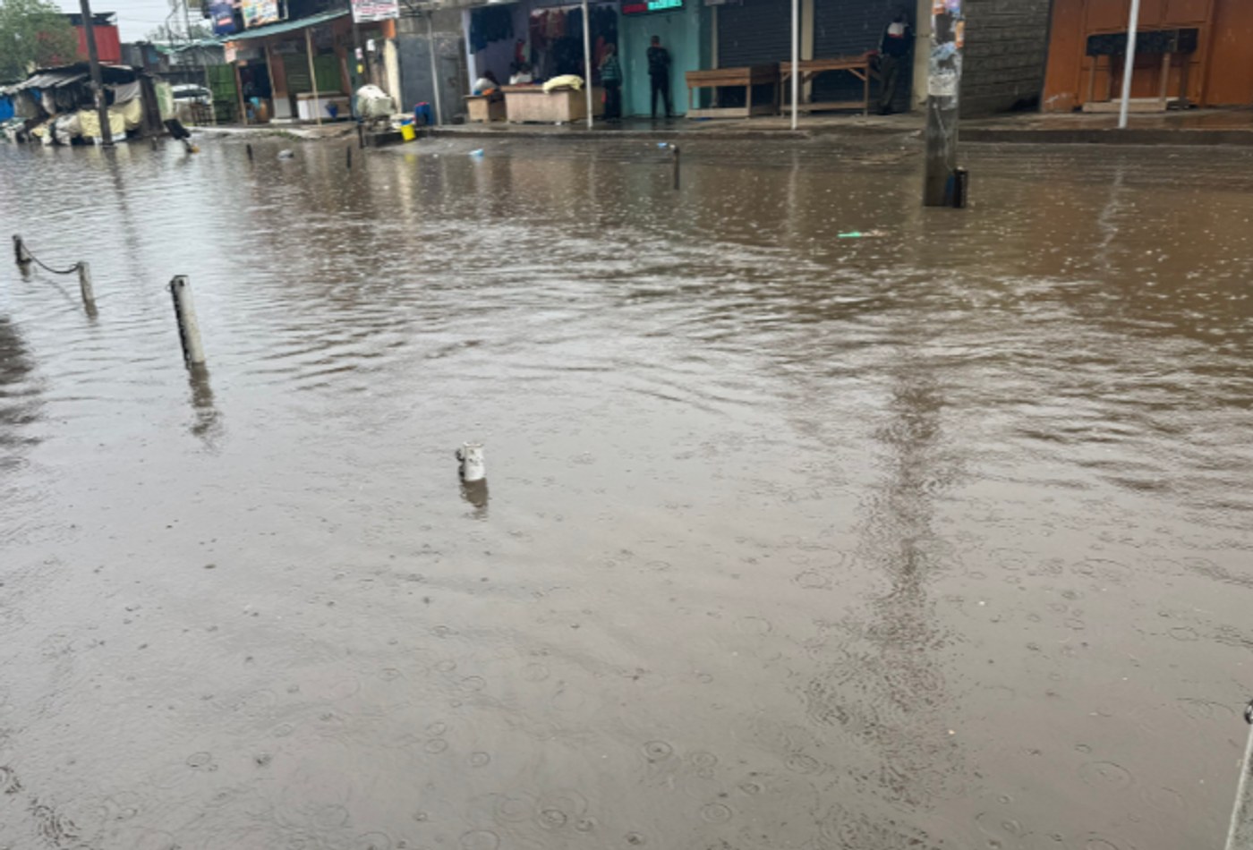 A street covered in brown floodwater, with buildings along one side.