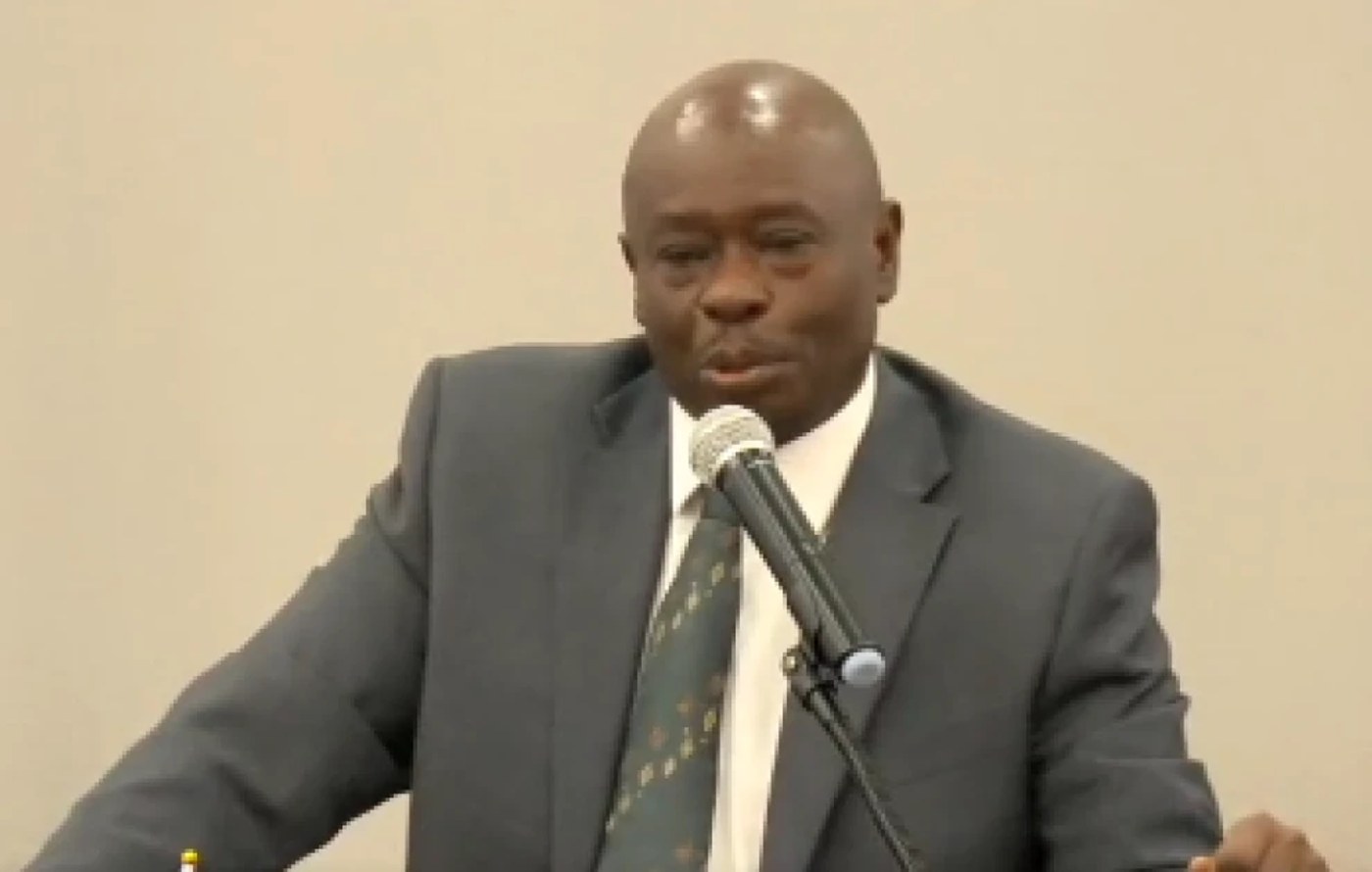 Rigathi Gachagua speaks into a microphone at an indoor meeting.