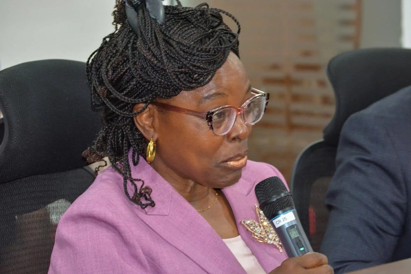 Controller of Budget Margaret Nyakang'o, in a pink jacket and glasses, speaks into a microphone.