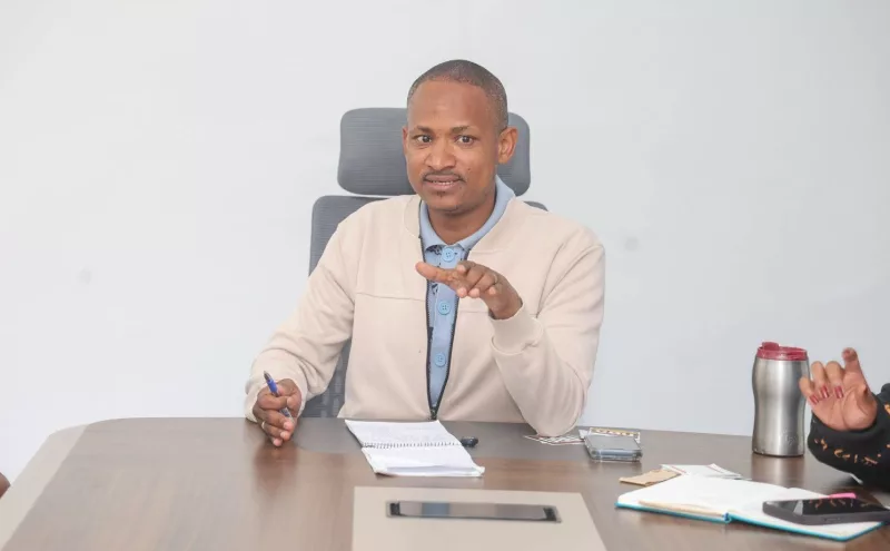 Babu Owino gestures while speaking from behind a desk.