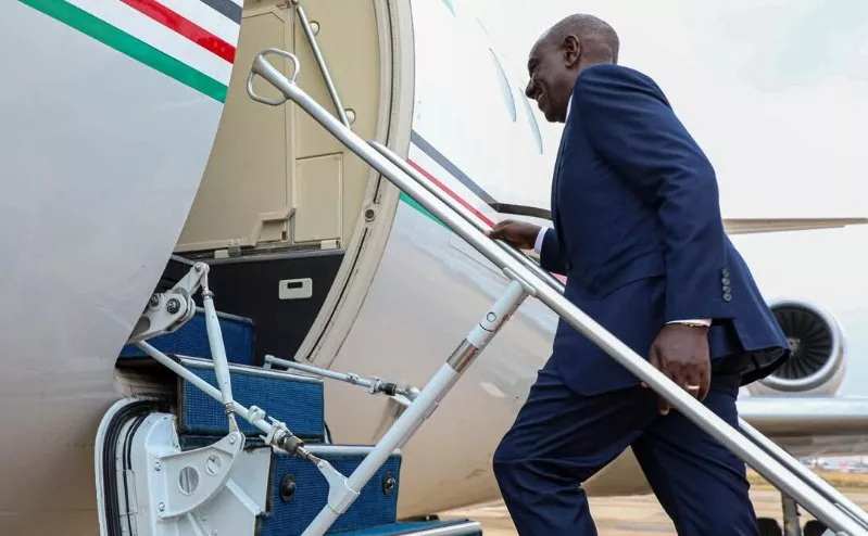 William Ruto climbs the stairs to an aircraft.